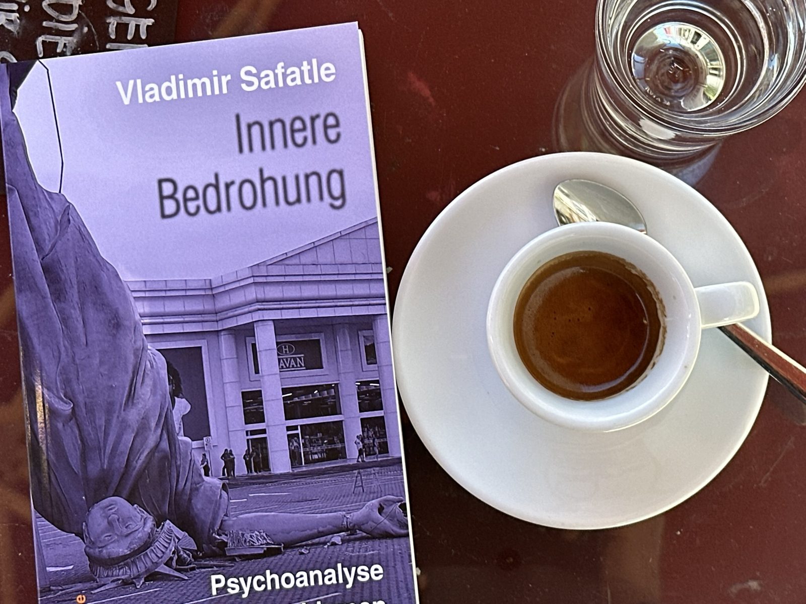 Vladimir Safatle: Innere Bedrohung. Psychoanalyse der neuen Faschismen, tentare Verlag – Taschenbuch mit violettem Cover neben einer Tasse Espresso auf einem Cafétisch