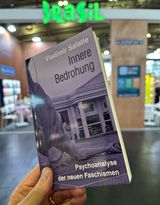 Vladimir Safatle: Innere Bedrohung. Psychoanalyse der neuen Faschismen, tentare Verlag – eine Hand hält das Buch vor einem Messestand mit grünem Leuchtschriftzug ›Brasil‹